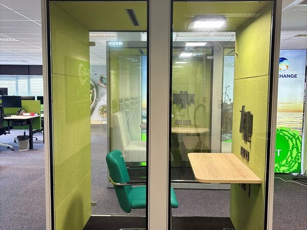 VOX Medium met groene stoffering en zwart frame als focusplek in de kantoortuin.